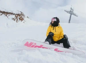 woman in a yellow jacket snowboarding at big white in kelowna